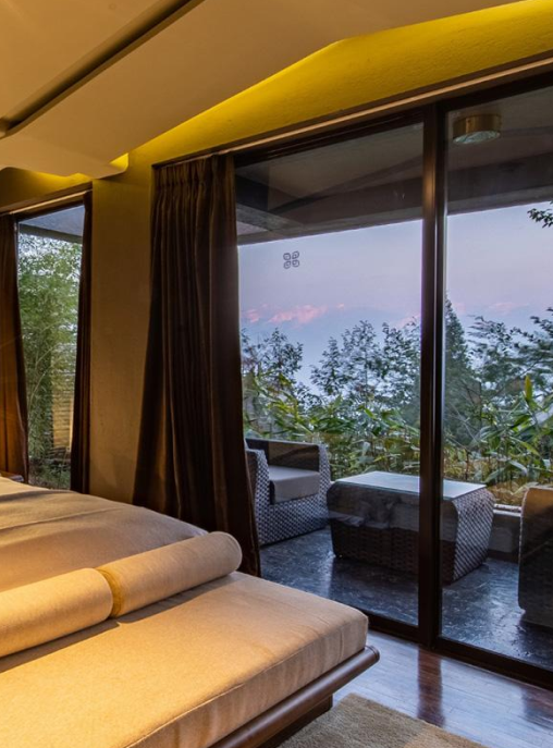 A bedroom with large window giving a view of a sitting area on the deck | Kavya Resort and Spa, Nagarkot